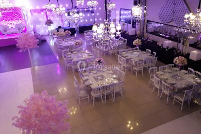 Salle colorée avec petites tables et chaises pour enfants, entourées de canapés aux motifs vifs sur un tapis décoré.