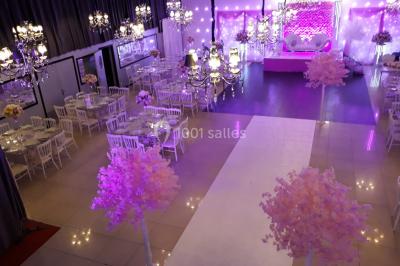 Salle colorée avec petites tables et chaises pour enfants, entourées de canapés aux motifs vifs sur un tapis décoré.