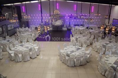 Salle colorée avec petites tables et chaises pour enfants, entourées de canapés aux motifs vifs sur un tapis décoré.