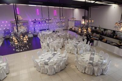 Salle colorée avec petites tables et chaises pour enfants, entourées de canapés aux motifs vifs sur un tapis décoré.