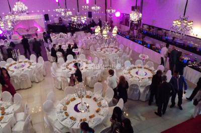 Salle colorée avec petites tables et chaises pour enfants, entourées de canapés aux motifs vifs sur un tapis décoré.