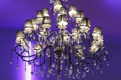 Salle colorée avec petites tables et chaises pour enfants, entourées de canapés aux motifs vifs sur un tapis décoré.