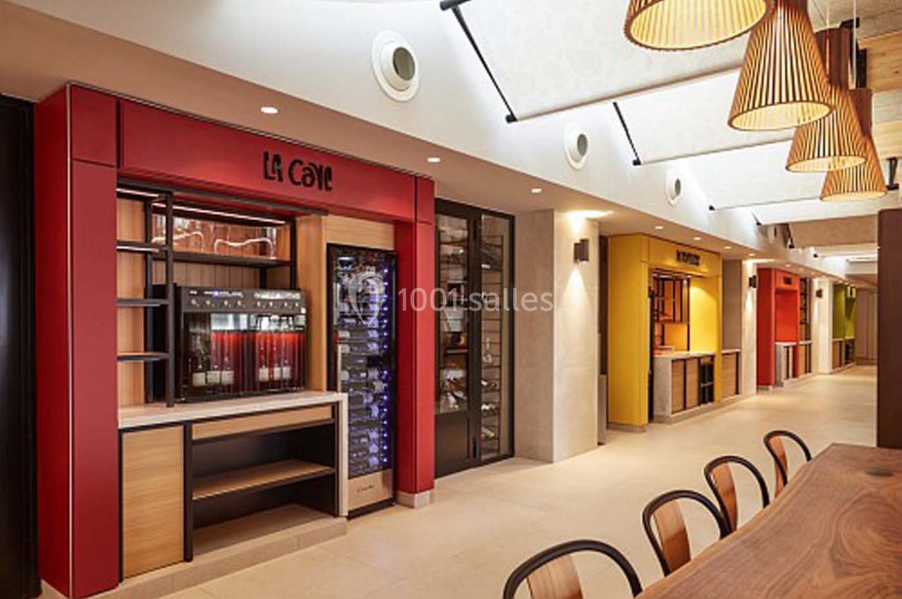 Intérieur d'un espace commercial moderne avec des étals colorés, un comptoir en bois et un éclairage suspendu.