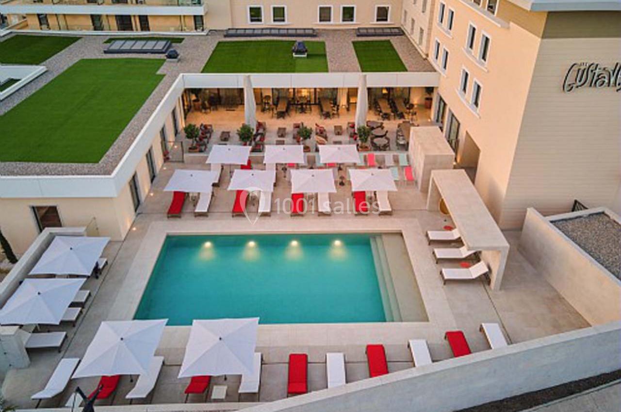 Vue aérienne d'une piscine extérieure entourée de chaises longues rouges et blanches avec des parasols, dans un complexe…