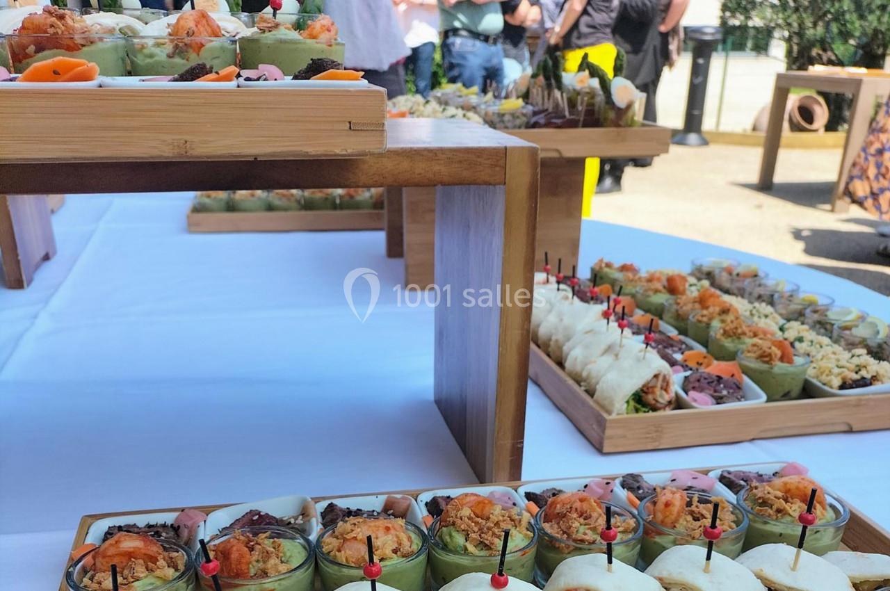 Buffet en extérieur avec des plateaux en bois garnis de verrines, wraps et autres amuse-bouches variés.