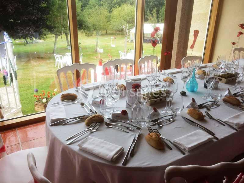 Location salle Audierne (Finistère) - Manoir de Menez Bras #7 Table dressée pour un repas, avec nappes blanches, couverts, verres et décorations, près d'une baie vitrée donnant sur un…