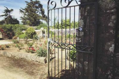 Miniature Location salle Audierne (Finistère) - Manoir de Menez Bras #4 Lit double avec couvre-lit rouge à motifs, encadré par deux tables de chevet, éclairé par des appliques murales.