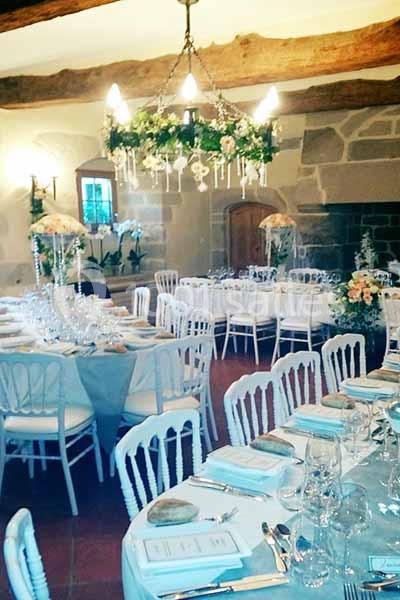 Location salle Audierne (Finistère) - Manoir de Menez Bras #8 Salle de réception décorée avec des tables dressées, des chaises blanches et un lustre orné de verdure.
