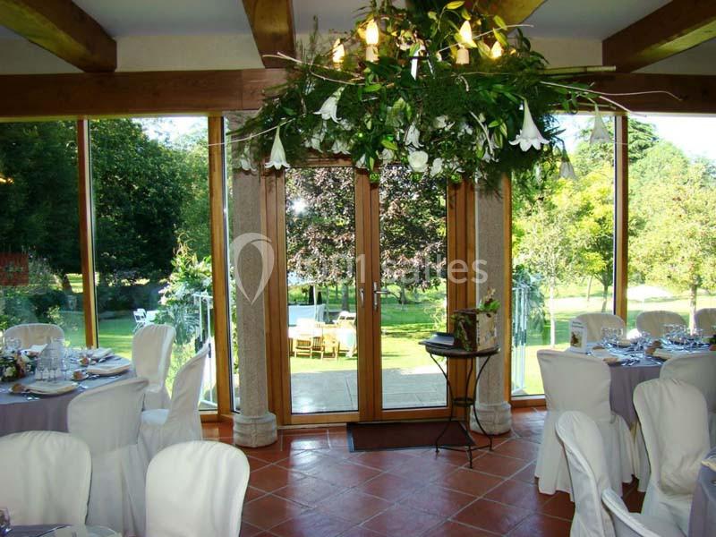 Location salle Audierne (Finistère) - Manoir de Menez Bras #12 Salle de réception lumineuse avec grandes baies vitrées donnant sur un jardin verdoyant, tables dressées élégamment.