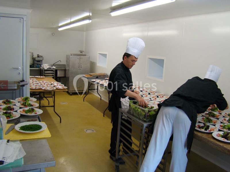 Location salle Audierne (Finistère) - Manoir de Menez Bras #16 Deux chefs préparent et dressent des assiettes avec des plats colorés dans une cuisine professionnelle lumineuse.