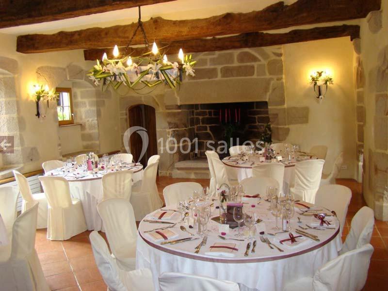 Location salle Audierne (Finistère) - Manoir de Menez Bras #14 Salle de réception rustique avec poutres apparentes, tables rondes dressées et cheminée en pierre.