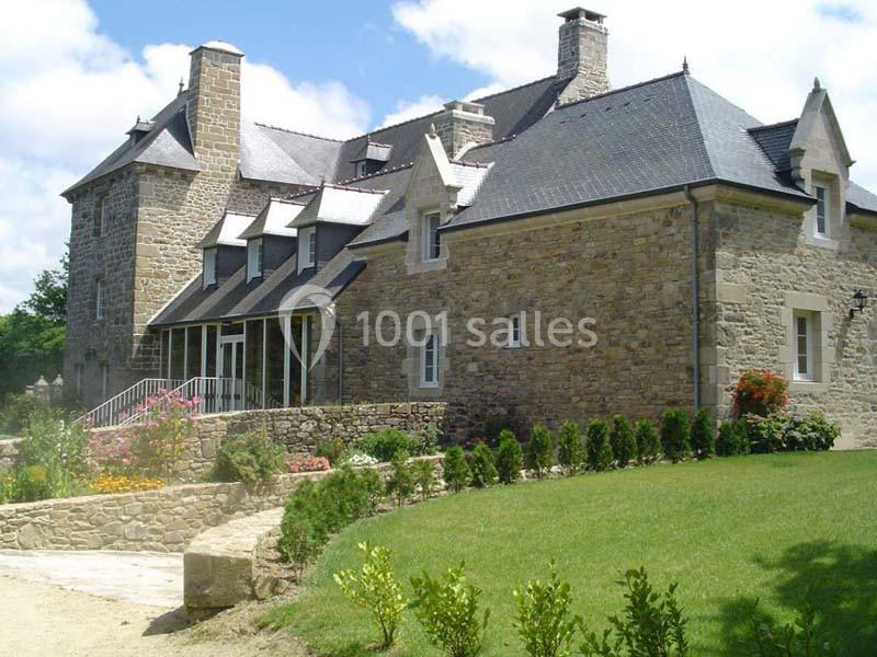 Location salle Audierne (Finistère) - Manoir de Menez Bras #2 Grande maison en pierre avec toit en ardoise, entourée d'un jardin verdoyant et d'allées fleuries.