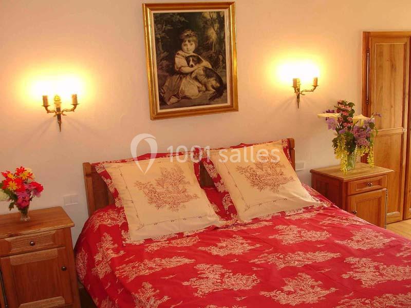 Location salle Audierne (Finistère) - Manoir de Menez Bras #22 Lit double avec couvre-lit rouge à motifs, encadré par deux tables de chevet, éclairé par des appliques murales.