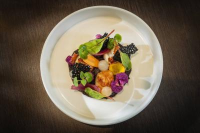 Mobilier de terrasse moderne avec vue sur un château médiéval sous un ciel bleu partiellement nuageux.