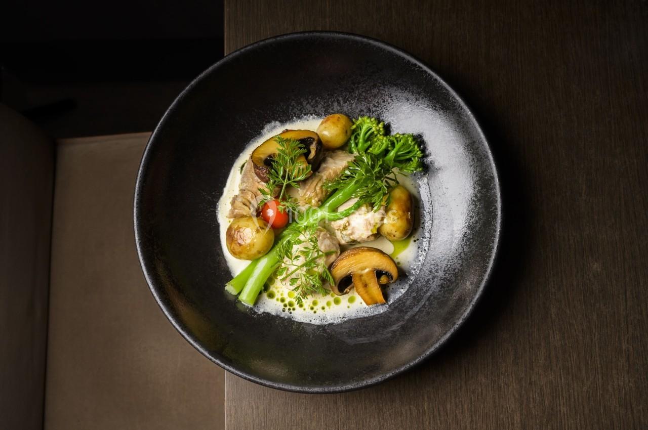 Assiette de légumes et champignons cuisinés, accompagnés de pommes de terre et d'une sauce crémeuse.