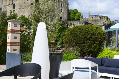 Mobilier de terrasse moderne avec vue sur un château médiéval sous un ciel bleu partiellement nuageux.