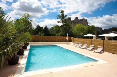 Mobilier de terrasse moderne avec vue sur un château médiéval sous un ciel bleu partiellement nuageux.