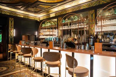 Escalier en marbre avec rampes en fer forgé, colonnes décoratives et lustres suspendus dans un intérieur ancien.