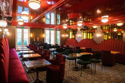 Escalier en marbre avec rampes en fer forgé, colonnes décoratives et lustres suspendus dans un intérieur ancien.