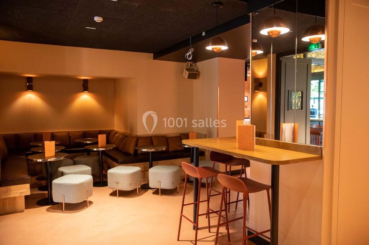 Espace intérieur moderne avec tables basses, tabourets, banquettes et éclairage tamisé.