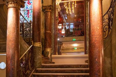 Groupe de personnes dans une salle ornée de miroirs et de lustres, avec un DJ jouant de la musique en arrière-plan.