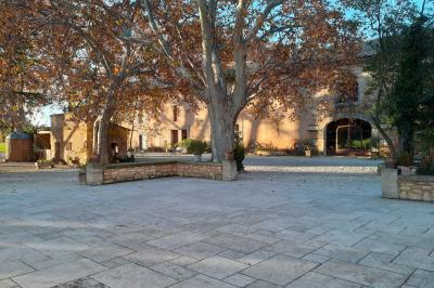 Bâtisse ancienne en pierre avec volets rouges, entourée d'arbres, sous un ciel partiellement nuageux.