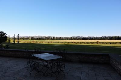 Bâtisse ancienne en pierre avec volets rouges, entourée d'arbres, sous un ciel partiellement nuageux.