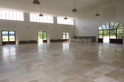 Bâtisse ancienne en pierre avec volets rouges, entourée d'arbres, sous un ciel partiellement nuageux.