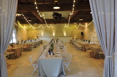 Bâtisse ancienne en pierre avec volets rouges, entourée d'arbres, sous un ciel partiellement nuageux.