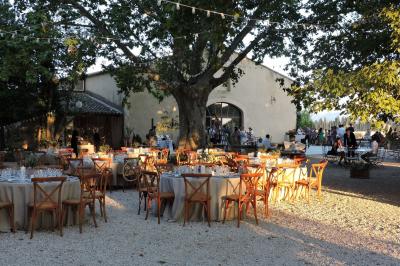 Bâtisse ancienne en pierre avec volets rouges, entourée d'arbres, sous un ciel partiellement nuageux.