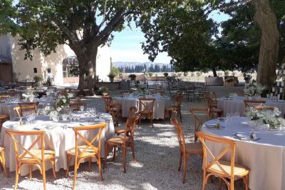 Bâtisse ancienne en pierre avec volets rouges, entourée d'arbres, sous un ciel partiellement nuageux.