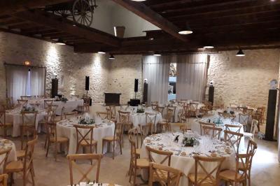 Bâtisse ancienne en pierre avec volets rouges, entourée d'arbres, sous un ciel partiellement nuageux.