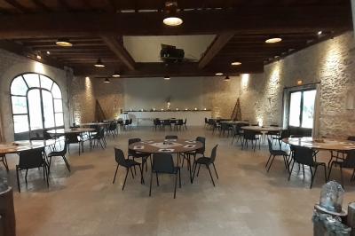 Bâtisse ancienne en pierre avec volets rouges, entourée d'arbres, sous un ciel partiellement nuageux.