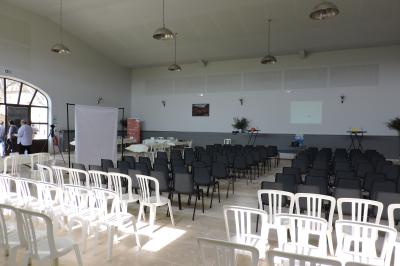 Bâtisse ancienne en pierre avec volets rouges, entourée d'arbres, sous un ciel partiellement nuageux.