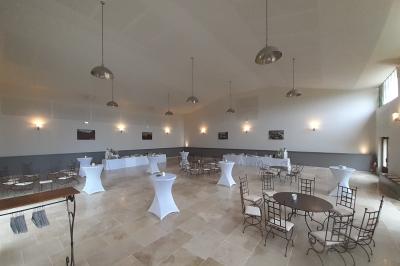 Bâtisse ancienne en pierre avec volets rouges, entourée d'arbres, sous un ciel partiellement nuageux.