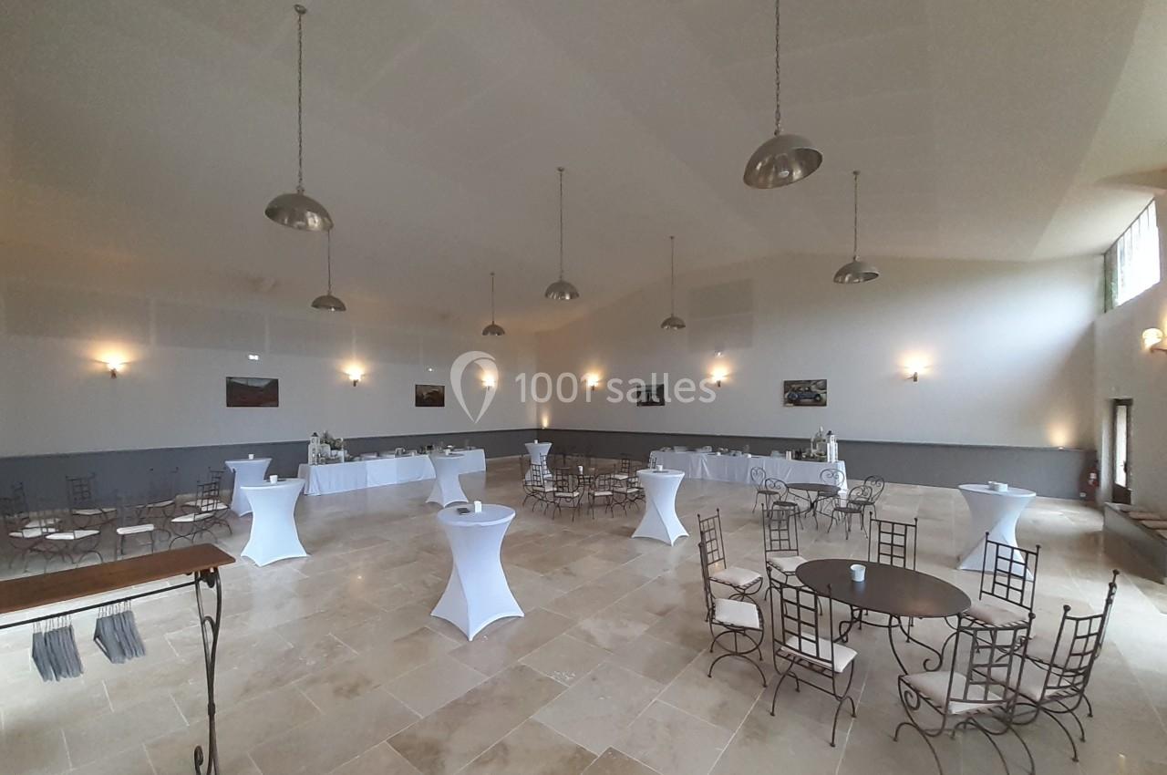 Salle de réception lumineuse avec tables rondes, chaises en métal et mange-debout, décor sobre et murs clairs.