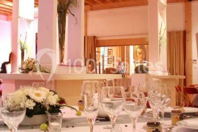Terrasse en bois longeant un bâtiment en briques avec vue sur un jardin arboré sous un ciel bleu.