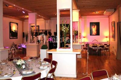 Terrasse en bois longeant un bâtiment en briques avec vue sur un jardin arboré sous un ciel bleu.