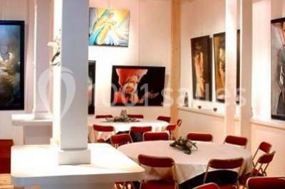 Terrasse en bois longeant un bâtiment en briques avec vue sur un jardin arboré sous un ciel bleu.