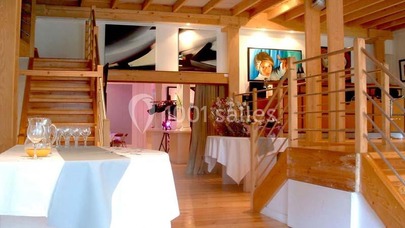Intérieur d'un restaurant avec escalier en bois, tables dressées et décoration lumineuse moderne.