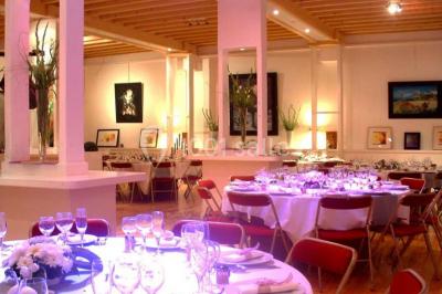 Terrasse en bois longeant un bâtiment en briques avec vue sur un jardin arboré sous un ciel bleu.