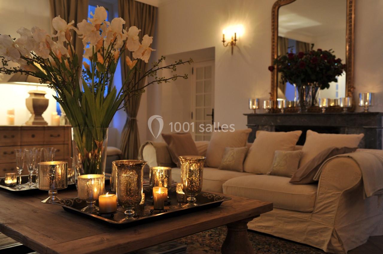 Salon chaleureux avec canapé beige, table en bois ornée de bougies et vase de fleurs, éclairage tamisé.