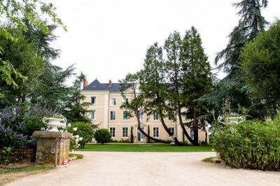 Deux jardinières sculptées sur un muret en pierre, entourées de végétation, avec une petite barrière en bois.