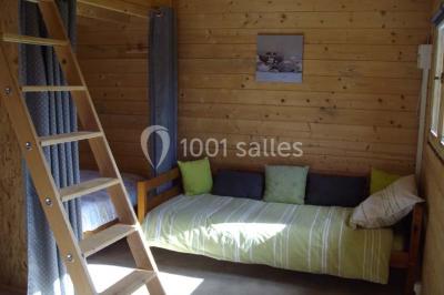 Des chèvres broutent de l'herbe dans un pré verdoyant, entourées d'arbres et d'une clôture en arrière-plan.