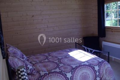 Des chèvres broutent de l'herbe dans un pré verdoyant, entourées d'arbres et d'une clôture en arrière-plan.