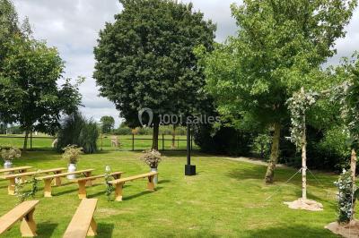 Des chèvres broutent de l'herbe dans un pré verdoyant, entourées d'arbres et d'une clôture en arrière-plan.