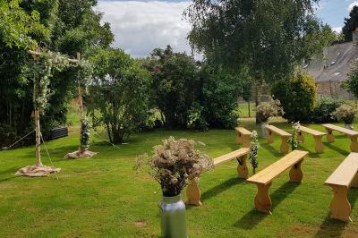 Des chèvres broutent de l'herbe dans un pré verdoyant, entourées d'arbres et d'une clôture en arrière-plan.