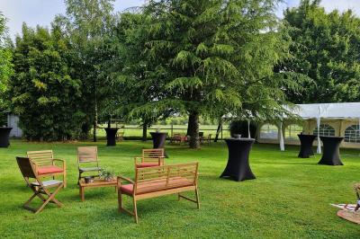 Des chèvres broutent de l'herbe dans un pré verdoyant, entourées d'arbres et d'une clôture en arrière-plan.
