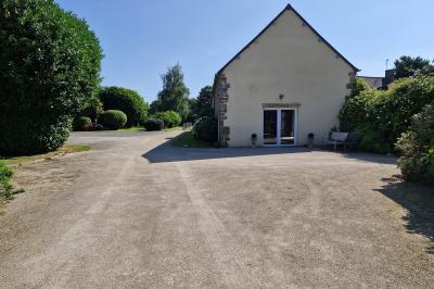 Des chèvres broutent de l'herbe dans un pré verdoyant, entourées d'arbres et d'une clôture en arrière-plan.