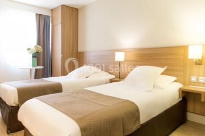 Ordinateur portable ouvert sur une table blanche avec carnet, tasse de café et plantes suspendues au-dessus.